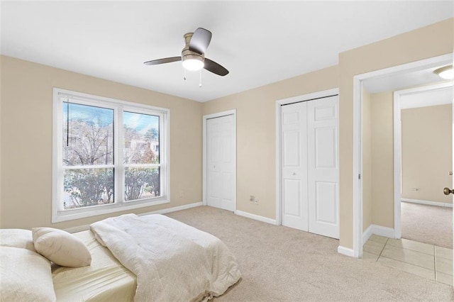 bedroom with multiple closets, light carpet, and ceiling fan