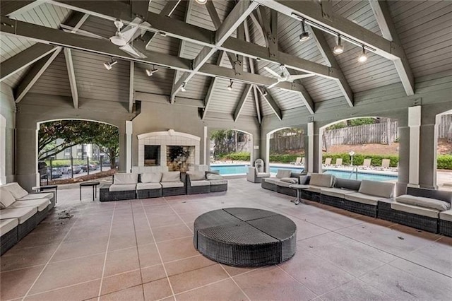 view of patio with an outdoor living space with a fireplace, a community pool, and ceiling fan