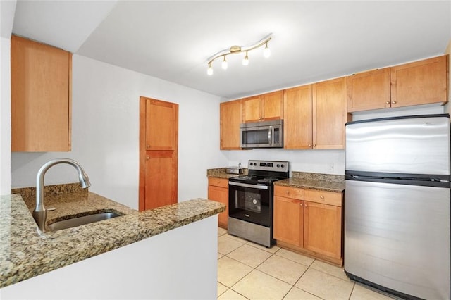 kitchen with sink, light tile patterned floors, stainless steel appliances, light stone counters, and kitchen peninsula