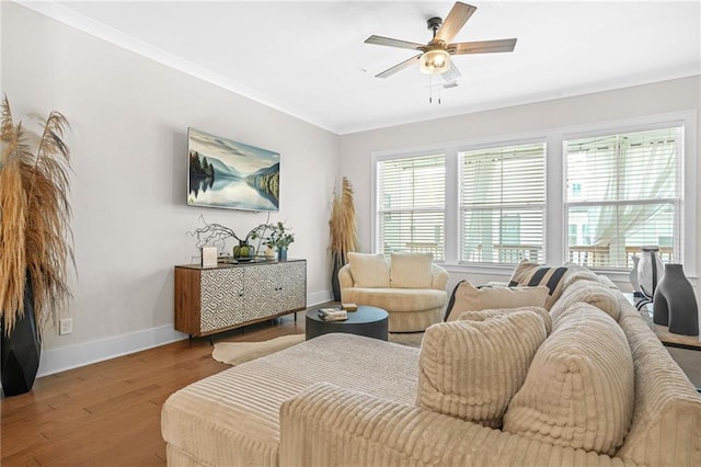 living area featuring baseboards, wood finished floors, crown molding, and ceiling fan