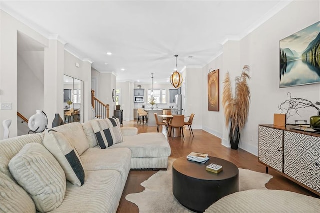 living area featuring wood finished floors, recessed lighting, ornamental molding, baseboards, and a chandelier