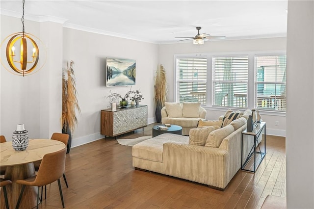 living room featuring ceiling fan, a chandelier, crown molding, wood finished floors, and baseboards
