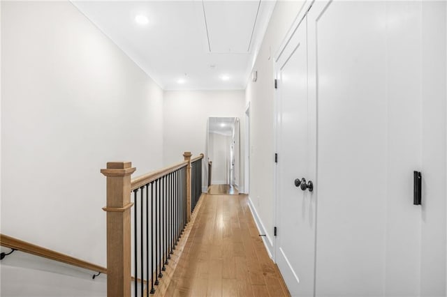 corridor with attic access, light wood-style flooring, baseboards, crown molding, and recessed lighting