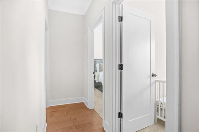 corridor featuring light wood finished floors and baseboards