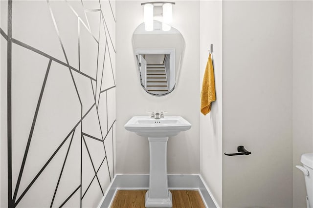 half bath with wood finished floors, toilet, and baseboards