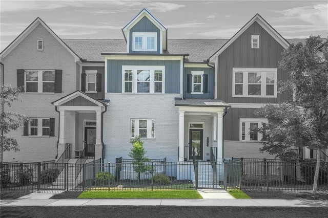 view of front of house with brick siding, board and batten siding, and a fenced front yard