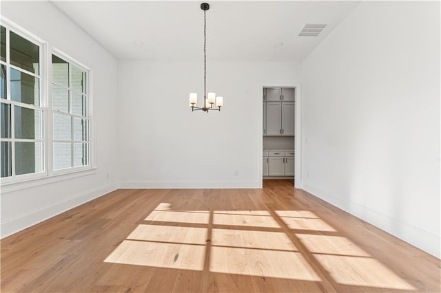 unfurnished dining area with a chandelier and light hardwood / wood-style flooring