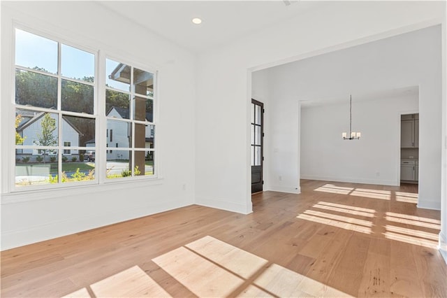 empty room with light hardwood / wood-style flooring and a chandelier