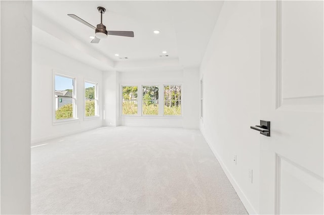 unfurnished room featuring a tray ceiling, ceiling fan, and light colored carpet