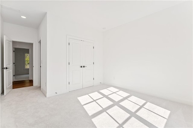 unfurnished bedroom featuring a closet and light colored carpet