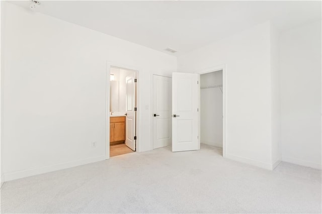 unfurnished bedroom with connected bathroom, light colored carpet, and a closet