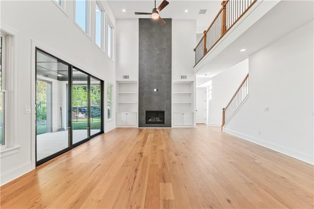 unfurnished living room with a wealth of natural light, ceiling fan, a high ceiling, and a fireplace