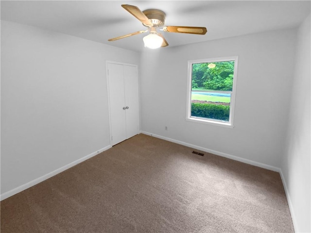 empty room featuring carpet floors, baseboards, and a ceiling fan