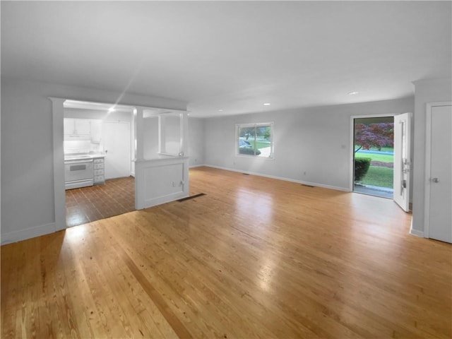 unfurnished living room with light wood-type flooring, baseboards, and recessed lighting