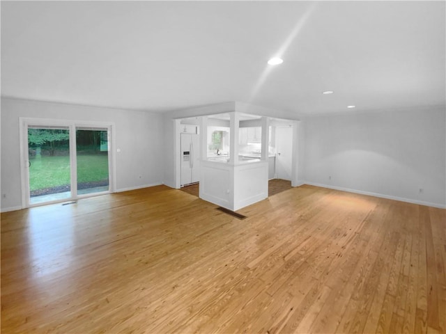 unfurnished living room with plenty of natural light, light wood-style floors, recessed lighting, and baseboards
