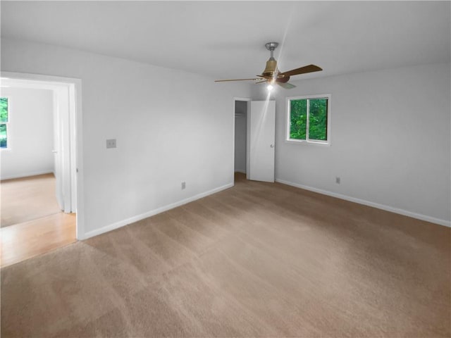 empty room with a ceiling fan, light colored carpet, and baseboards