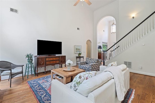living area featuring visible vents, arched walkways, a ceiling fan, and a high ceiling