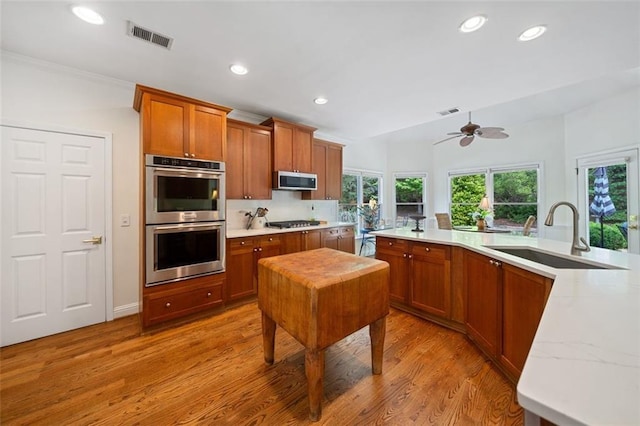 kitchen with ceiling fan, visible vents, a sink, light wood finished floors, and stainless steel appliances