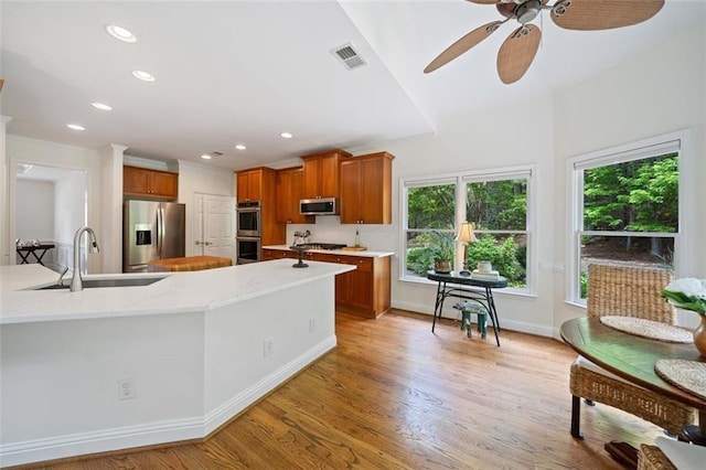 kitchen with visible vents, brown cabinets, a sink, a wealth of natural light, and stainless steel appliances