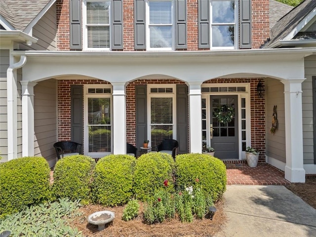 property entrance featuring covered porch and brick siding