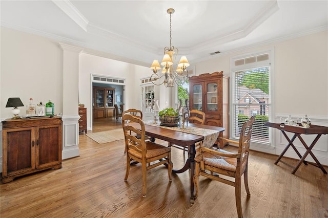 dining space featuring light wood-style floors, ornamental molding, decorative columns, and a notable chandelier