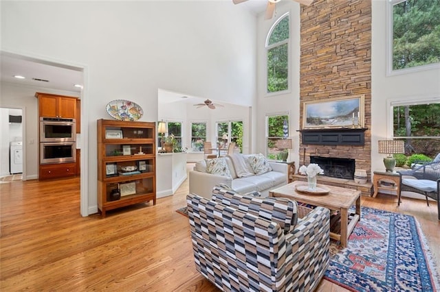 living area featuring light wood-style floors, a ceiling fan, washer / clothes dryer, and a high ceiling