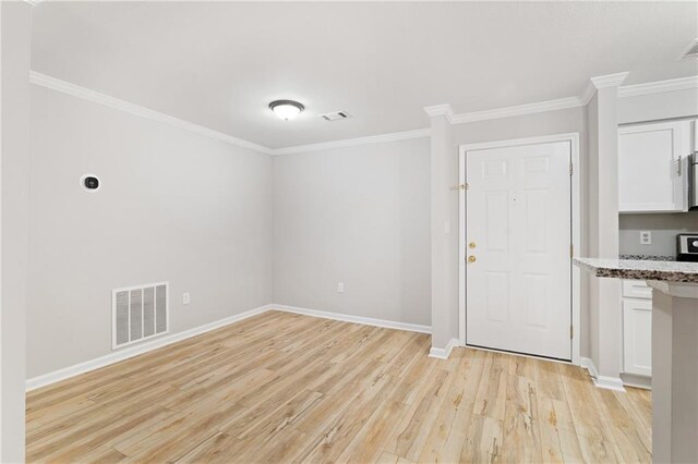 interior space with crown molding, light stone countertops, light hardwood / wood-style flooring, and white cabinets