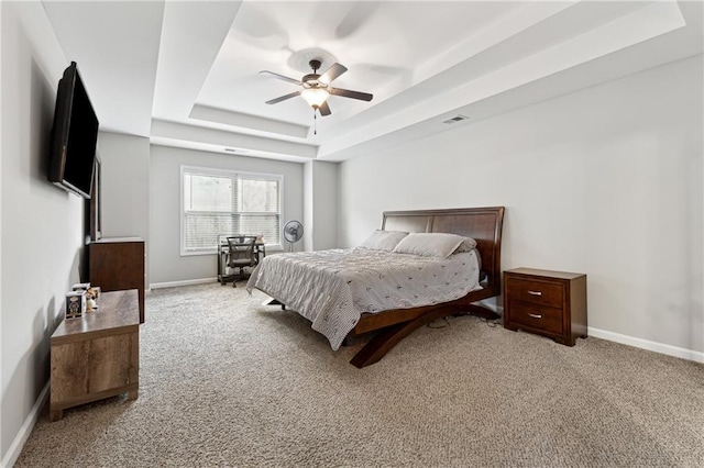 bedroom featuring light carpet, a raised ceiling, and ceiling fan