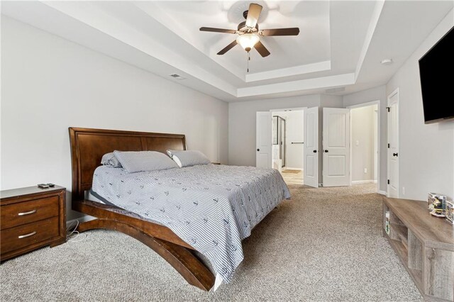 carpeted bedroom featuring a tray ceiling and ceiling fan