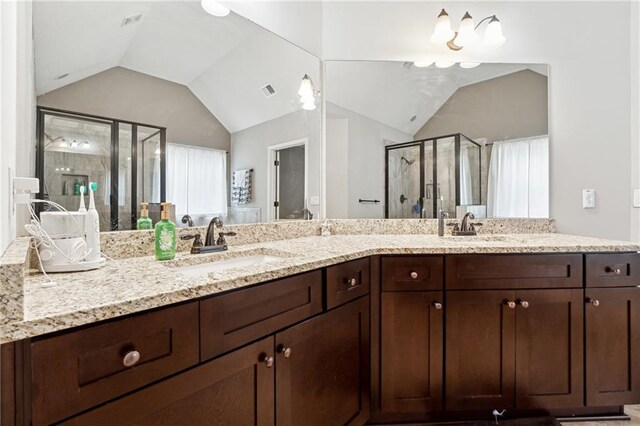 bathroom featuring vanity, an inviting chandelier, walk in shower, and vaulted ceiling