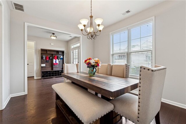 dining area featuring dark hardwood / wood-style floors, a healthy amount of sunlight, and an inviting chandelier