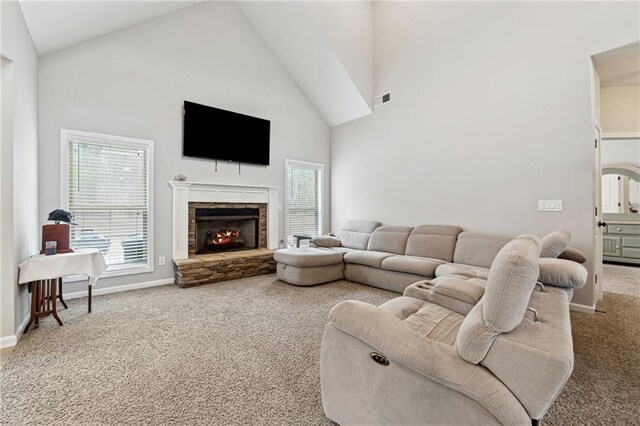 living room with carpet flooring, a stone fireplace, and high vaulted ceiling