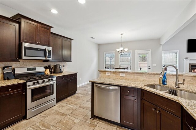 kitchen with dark brown cabinetry, stainless steel appliances, sink, decorative light fixtures, and a chandelier