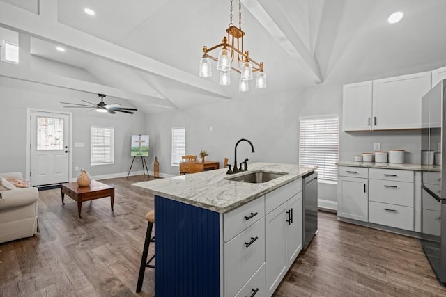 kitchen with stainless steel dishwasher, a sink, white cabinetry, and open floor plan