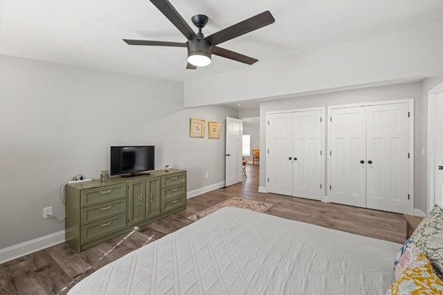 bedroom featuring baseboards, two closets, and dark wood-style floors