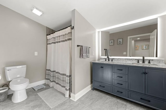 full bathroom featuring a sink, baseboards, toilet, and double vanity