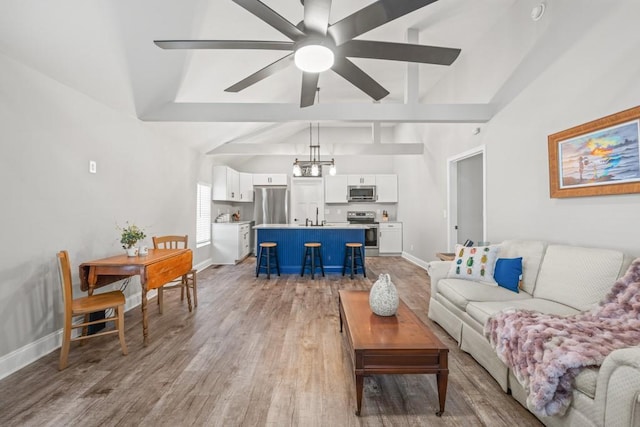 living area featuring a ceiling fan, baseboards, lofted ceiling with beams, and light wood-style flooring