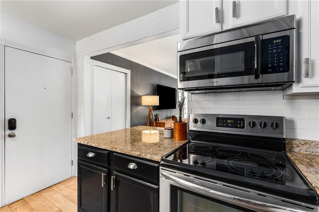 2240 Cheshire Bridge Rd NE Unit 206, Atlanta, GA 30324 - kitchen with appliances with stainless steel finishes, dark cabinetry, backsplash, light stone counters, and white cabinets