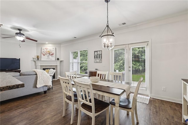 13468 Gardiner Ln, Alpharetta, GA 30004 - dining room featuring ornamental molding, a fireplace, dark wood finished floors, a chandelier, and a ceiling fan