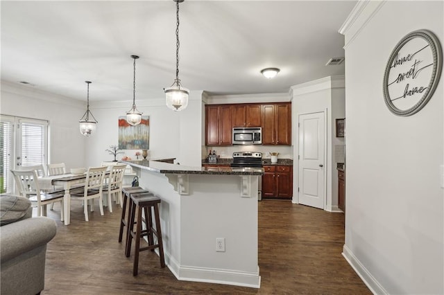 13468 Gardiner Ln, Alpharetta, GA 30004 - kitchen with appliances with stainless steel finishes, a kitchen bar, ornamental molding, dark wood-style floors, and pendant lighting