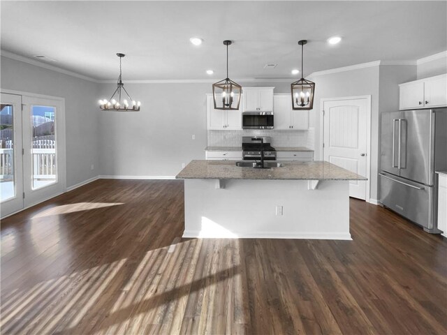 kitchen with decorative backsplash, light stone counters, appliances with stainless steel finishes, dark wood-style flooring, and a notable chandelier