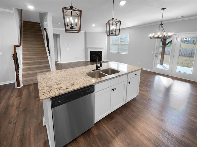 kitchen with crown molding, open floor plan, a kitchen island with sink, a sink, and dishwasher