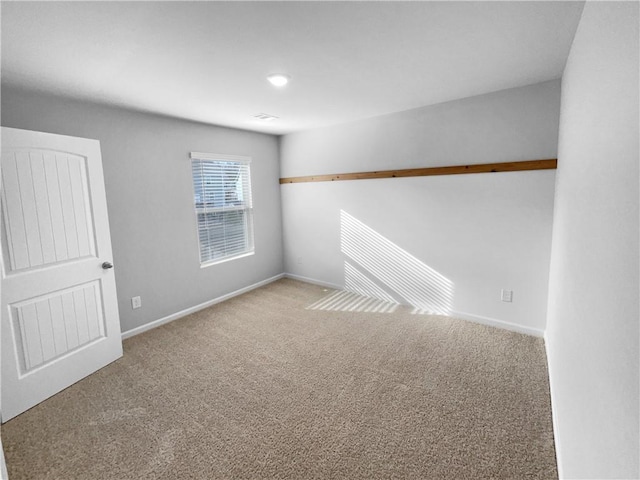 carpeted empty room featuring baseboards