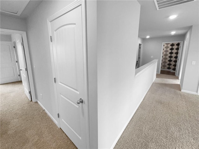 hall featuring baseboards, recessed lighting, visible vents, and light colored carpet