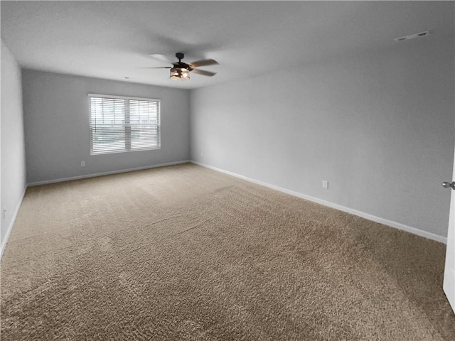 carpeted empty room featuring ceiling fan and baseboards