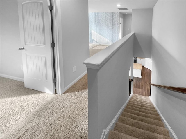 stairs with carpet floors, visible vents, and baseboards