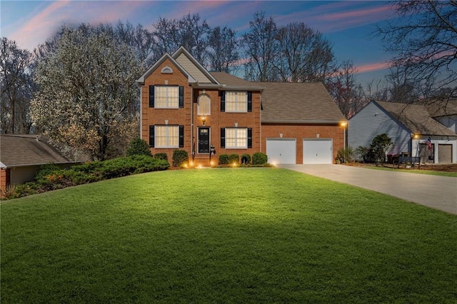 colonial inspired home with an attached garage, a lawn, brick siding, and driveway