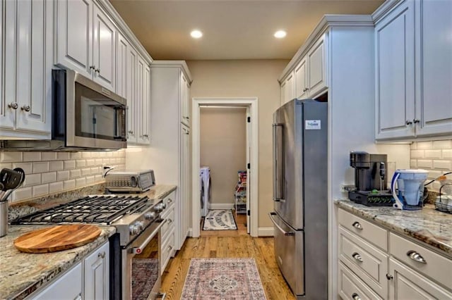 502 Cottage Crest Dr, Clarkesville, GA 30523 - kitchen featuring stainless steel appliances, washer and clothes dryer, light wood finished floors, decorative backsplash, and recessed lighting