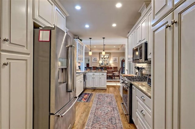 502 Cottage Crest Dr, Clarkesville, GA 30523 - kitchen featuring stainless steel appliances, light wood finished floors, a peninsula, recessed lighting, and pendant lighting