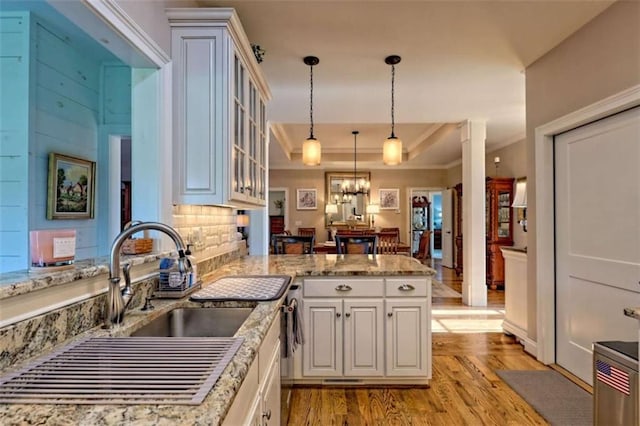 502 Cottage Crest Dr, Clarkesville, GA 30523 - kitchen featuring light wood-type flooring, a peninsula, a chandelier, ornamental molding, and glass insert cabinets
